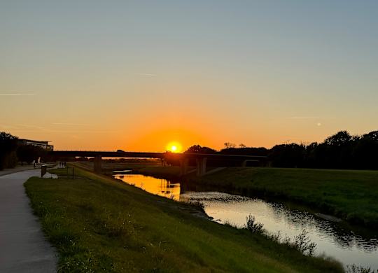 Riverside Walking Path with Bridge and Sunset Glow Near The Elm at River Park