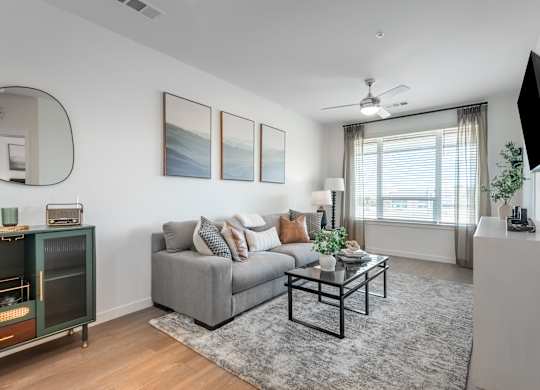 A living room with a grey couch, a coffee table, a television, and a painting on the wall.