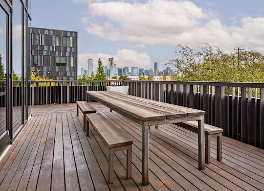 A wooden deck with a bench and a table with a metal frame.