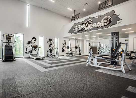 A gym with a variety of equipment including treadmills, weights, and exercise machines.