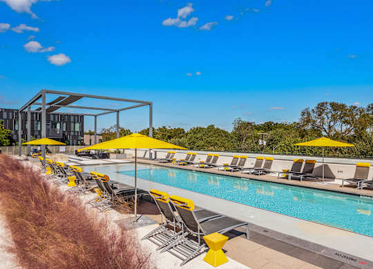 A pool area with sun loungers and umbrellas.