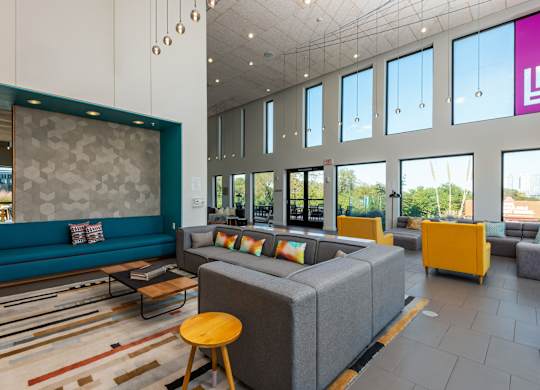A modern living room with a grey sofa and a yellow stool.