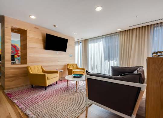 A living room with a brown couch and a television mounted on the wall.