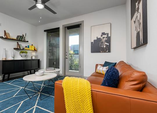 A living room with a brown leather couch and a yellow throw blanket.