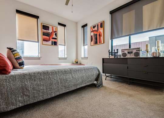A room with a bed, a cabinet, and two windows.