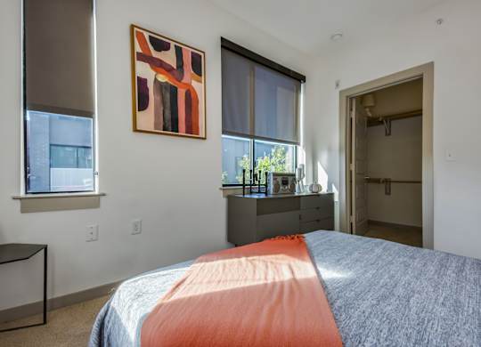 A bedroom with a bed, nightstand, and a painting on the wall.