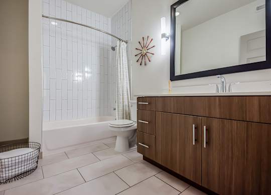 A bathroom with a toilet, a shower, and a mirror.