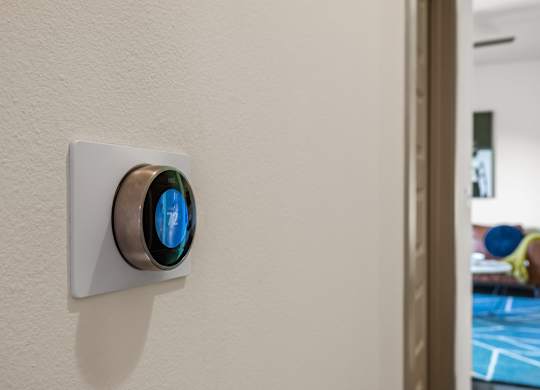 A wall-mounted thermostat with a blue light on it.