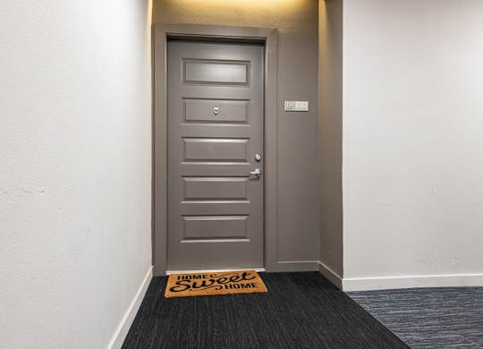 A grey door with a sign on the floor that says