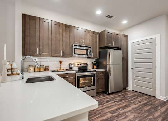 A modern kitchen with brown cabinets and stainless steel appliances.