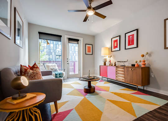 A living room with a grey couch, a yellow table, and a colorful rug.
