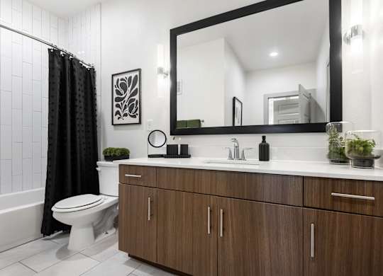 Updated Bathroom Featuring Wide Mirror, Tub, and Chrome Fixtures