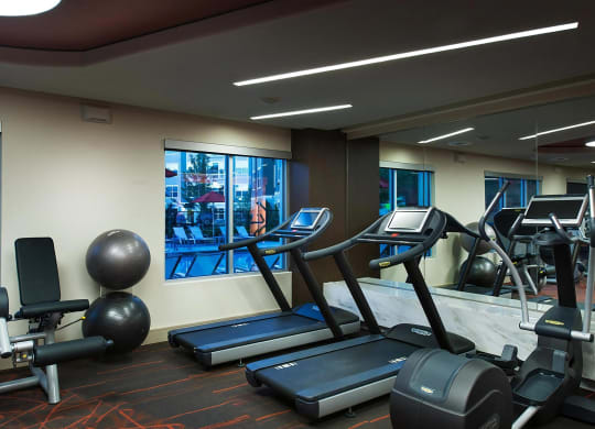 24-Hour Fitness Center with Cardio Machines and Mirrors