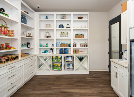 a kitchen with white cabinets and shelves and a refrigerator