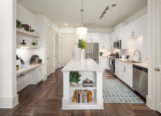 a white kitchen with a white island and stainless steel appliances