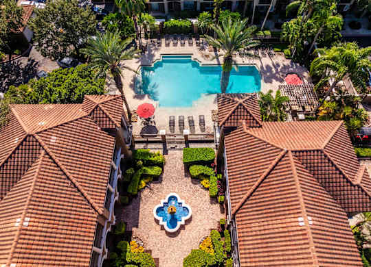 Aerial view of apartments near clubhouse with pool and landscaped greenery