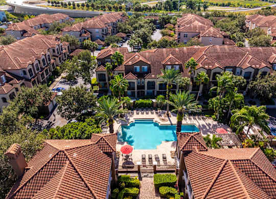 Aerial perspective of pool, clubhouse, and surrounding residential buildings