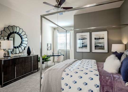 Bedroom with canopy bed, dark dresser, and decorative mirror accent