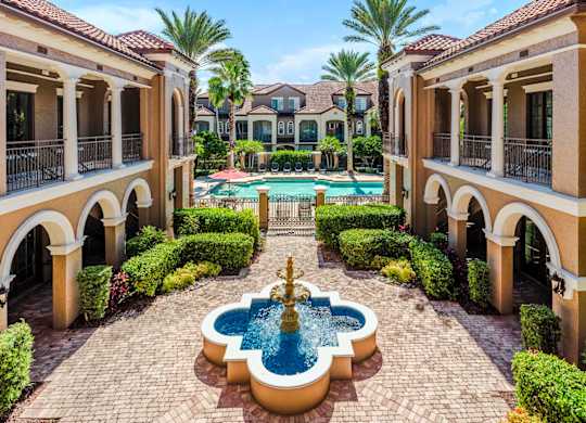 Tranquil courtyard fountain framed by palm trees and Mediterranean-style architecture.