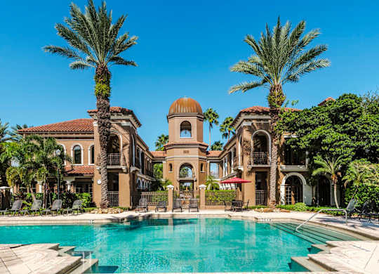 Grand pool courtyard framed by Mediterranean buildings and a central tower