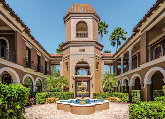 Mediterranean-style courtyard with a signature fountain surrounded by lush greenery and pathways.