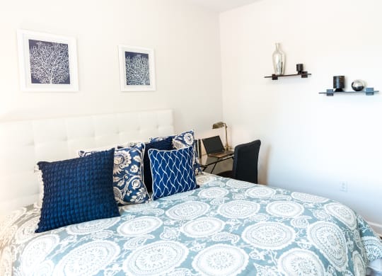 a bedroom with a bed with blue and white bedding and blue pillows