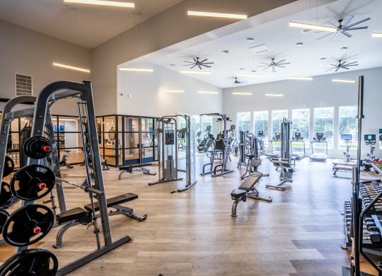 a large fitness room with cardio equipment and glass windows