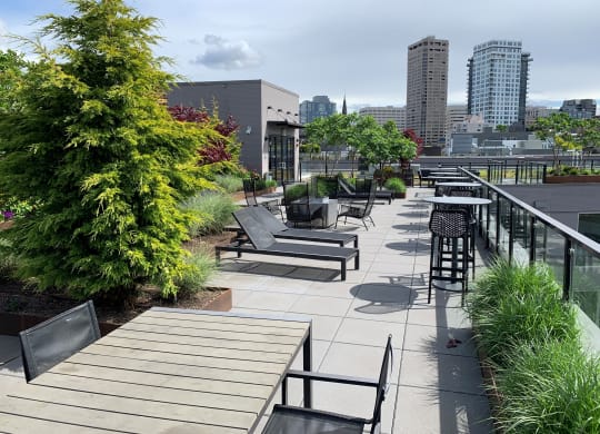 a roof deck with benches and tables and a city in the background