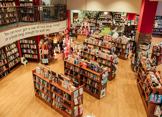 A book store with many book shelves and a sign that says you can never get a cup of tea large enough or a book long enough.