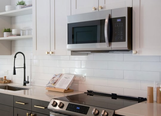 Sophisticated white countertops with subway tile backsplash and dark cabinets at Novel Cary
