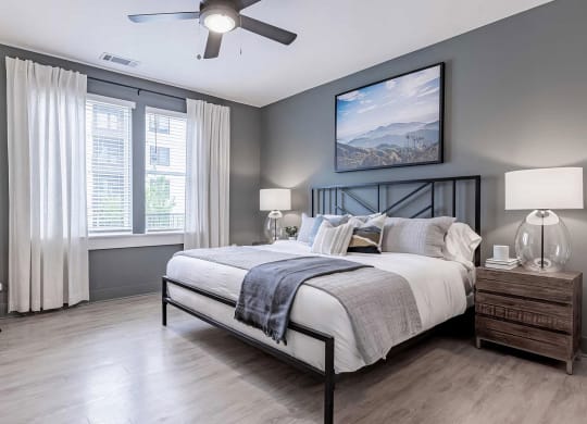 Spacious primary bedroom with dark gray walls and ceiling fan at Novel Cary