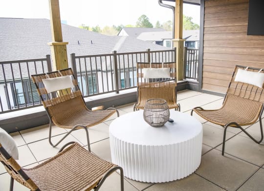 Cozy balcony with wicker style chairs and large flatscreen television at Novel Cary