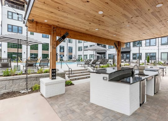 Full outdoor countertop with refrigerators under a modern pergola next to the pool at Novel Cary