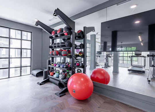 Spacious free-weight area with kettlebells, exercise balls, and floor mats at Novel Cary