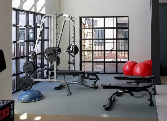 Weight rack with several benches in fitness area with extra tall ceilings at Novel Cary