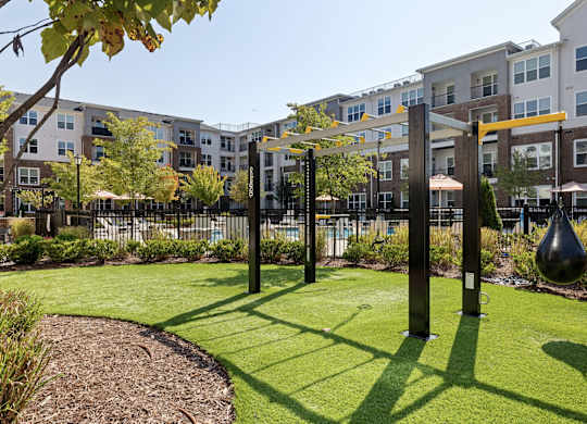 A playground with a swing set and a slide in the foreground and apartment buildings in the background.