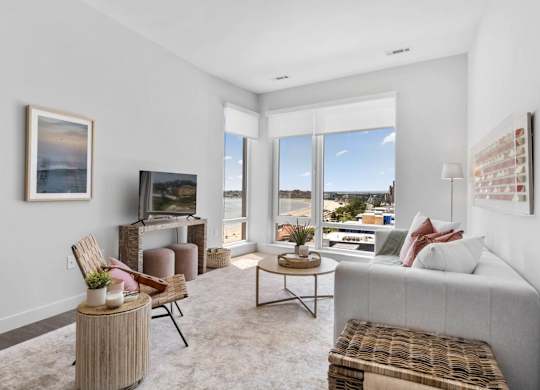 A living room with a grey couch, a wooden table, and a painting on the wall.