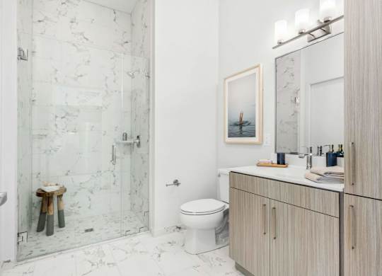 A bathroom with a toilet, sink, and a picture of a boat on the wall.