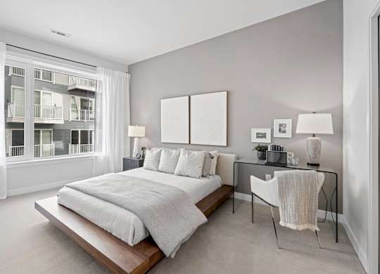 A bedroom with a large bed and a desk with a chair.