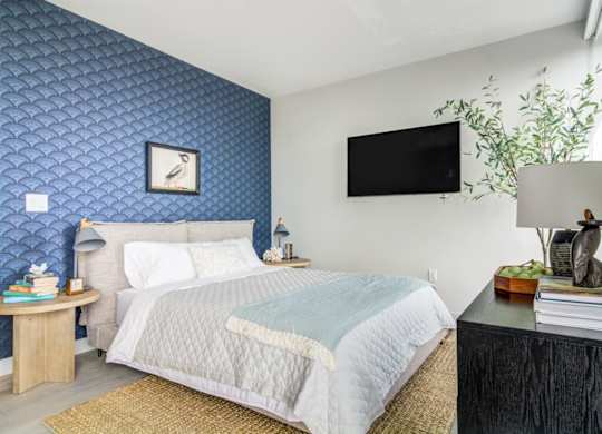 A bedroom with a bed, nightstand, and a wall clock.