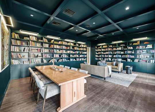 A room with a long table surrounded by bookshelves filled with books.