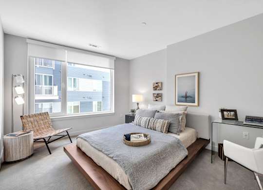 A bedroom with a large bed, a chair, and a desk.