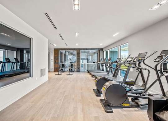 A gym with treadmills and a view of the outside.