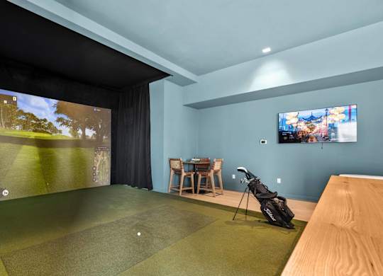 A golf simulator room with a screen showing a golf course.