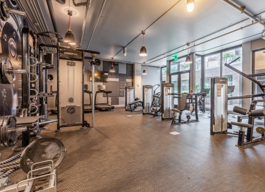 a gym with weights and cardio equipment in a building with windows