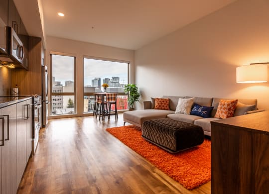 a living room with a couch and a rug and a kitchen