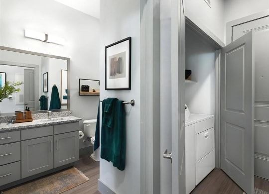 Entryway View Showing Bathroom with Granite Countertop and In-Unit Laundry Closet