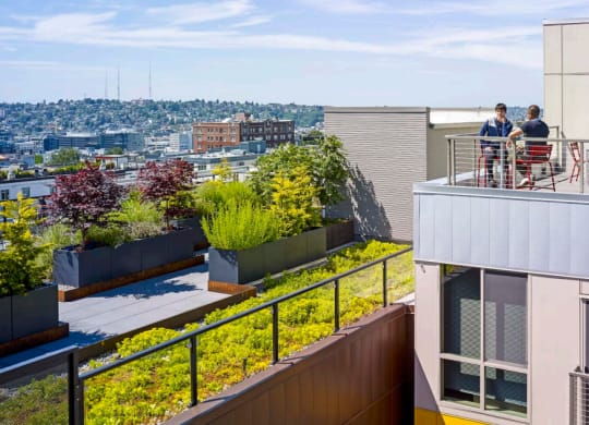 a roof terrace with a view of the city and people sitting on a balcony