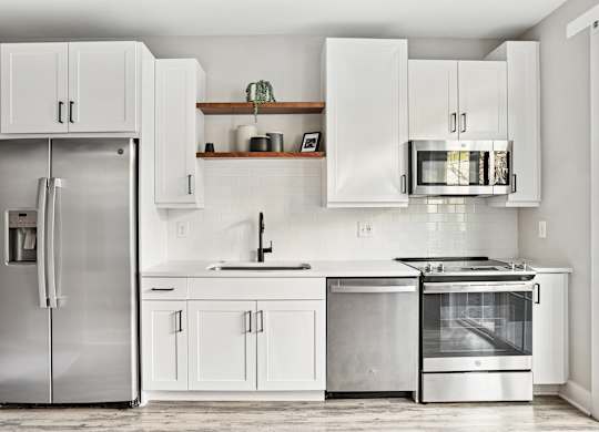 A modern kitchen with a stainless steel refrigerator and oven.