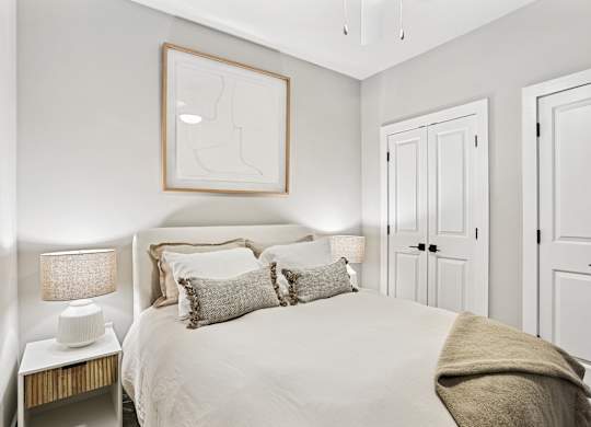 A bedroom with a bed, two lamps, and a picture on the wall.